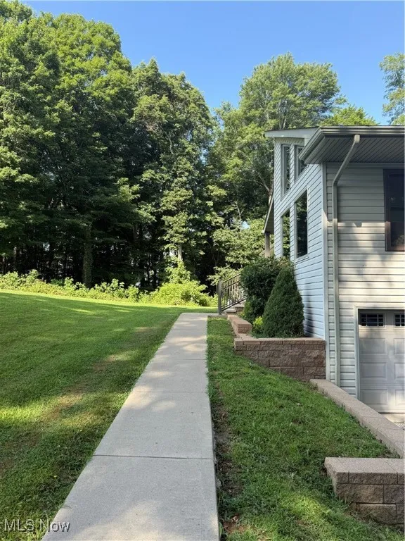 View of property exterior featuring a yard and an attached garage
