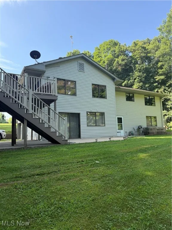 Back of property with stairs, a lawn, and a patio