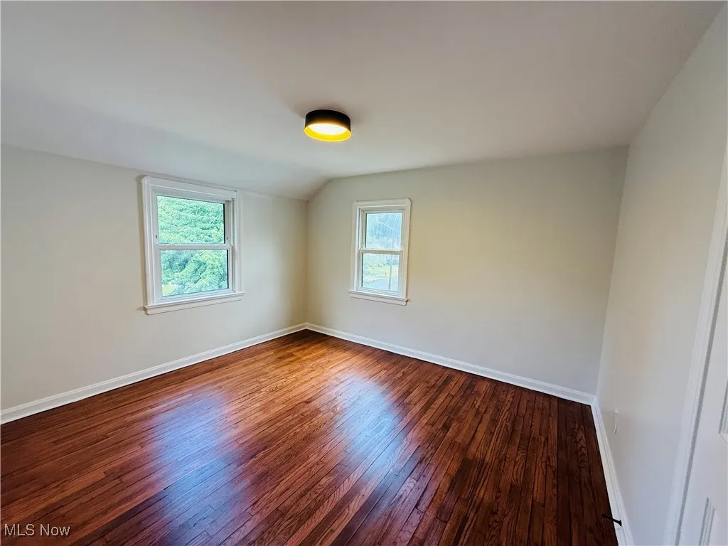 Spare room with wood finished floors and vaulted ceiling