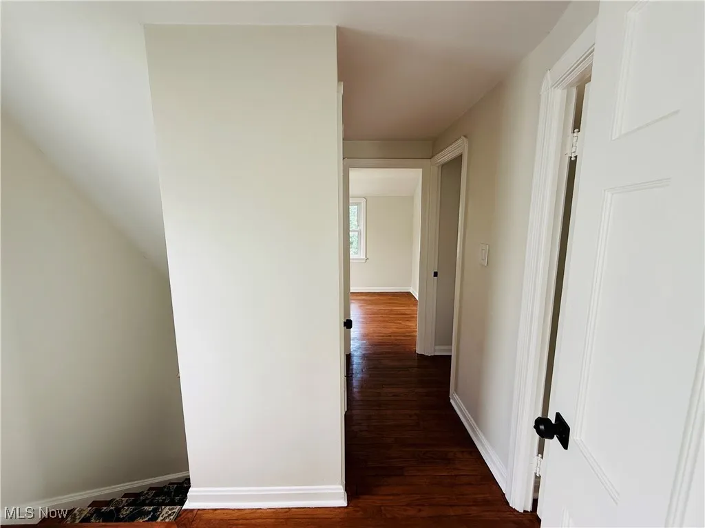 Hallway featuring dark wood finished floors and baseboards