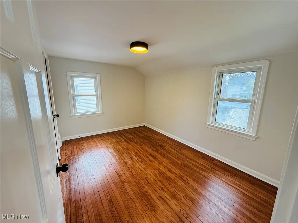 Spare room with hardwood / wood-style floors and vaulted ceiling