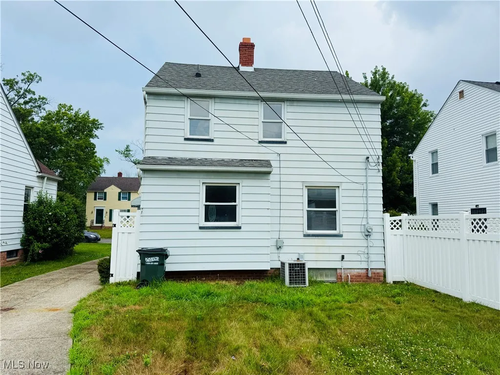 Back of property featuring a chimney and roof with shingles