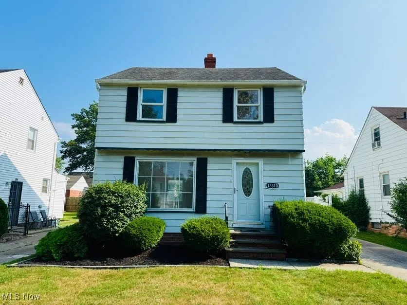 Colonial home with a chimney and a front lawn
