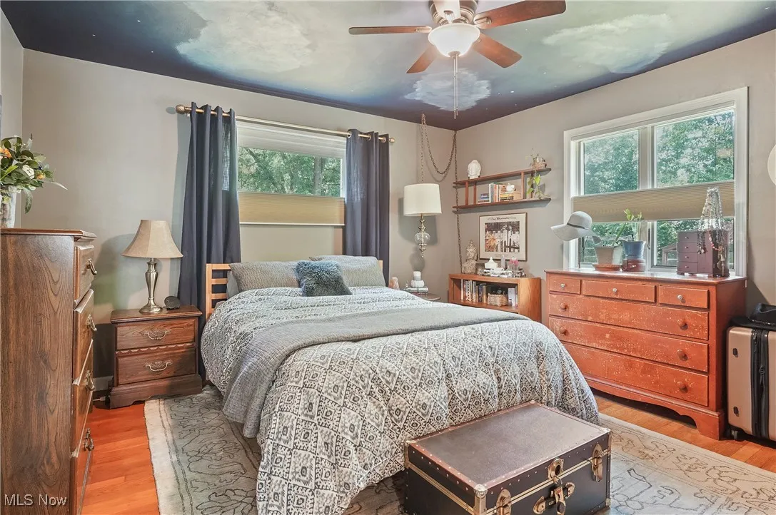 Owners Bedroom featuring multiple windows, light wood finished floors, and ceiling fan