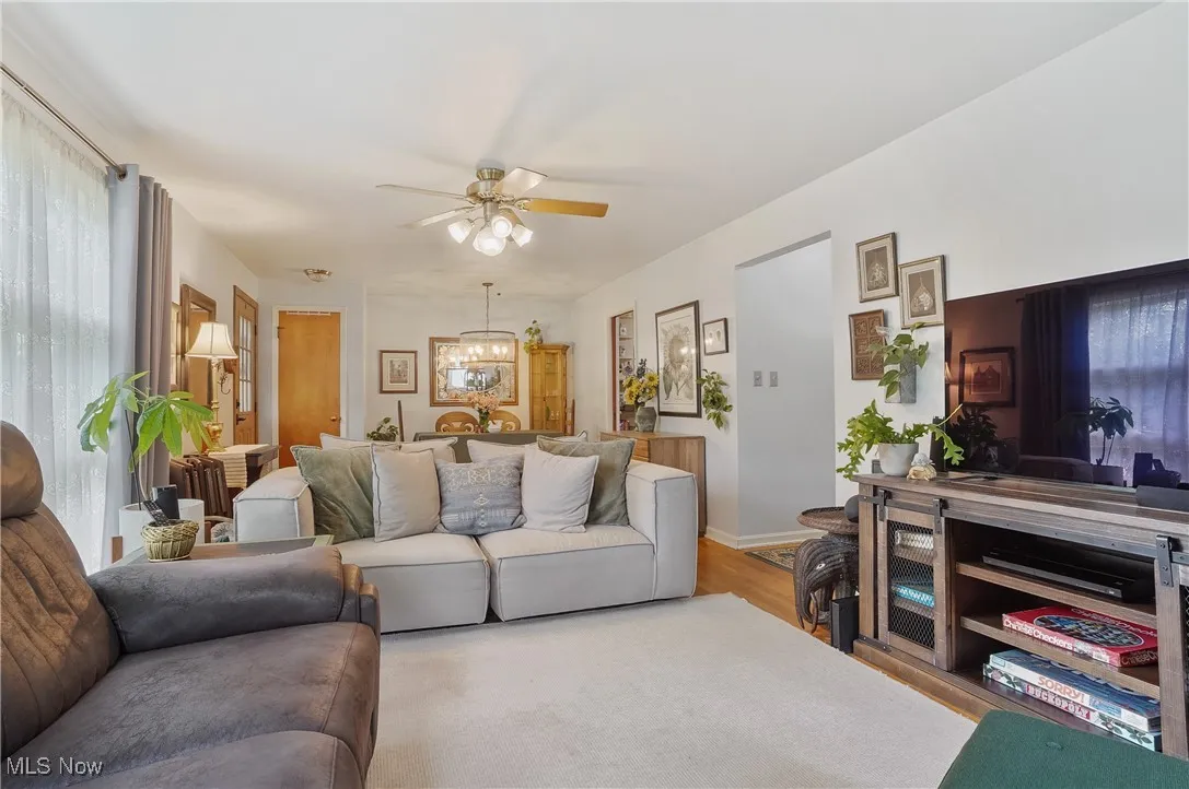 Living area featuring a chandelier, wood finished floors, and a ceiling fan