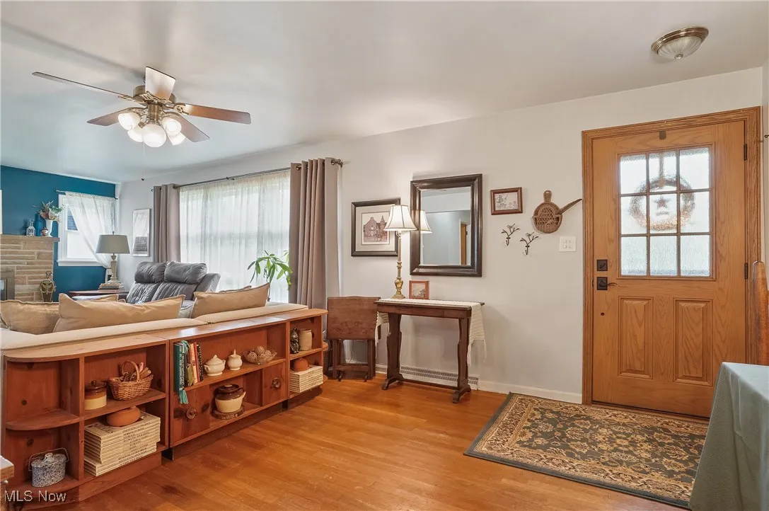 Foyer entrance with a ceiling fan, light wood flooring, and a fireplace