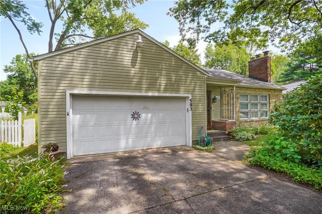 View of front of home with a chimney, an attached garage, and driveway