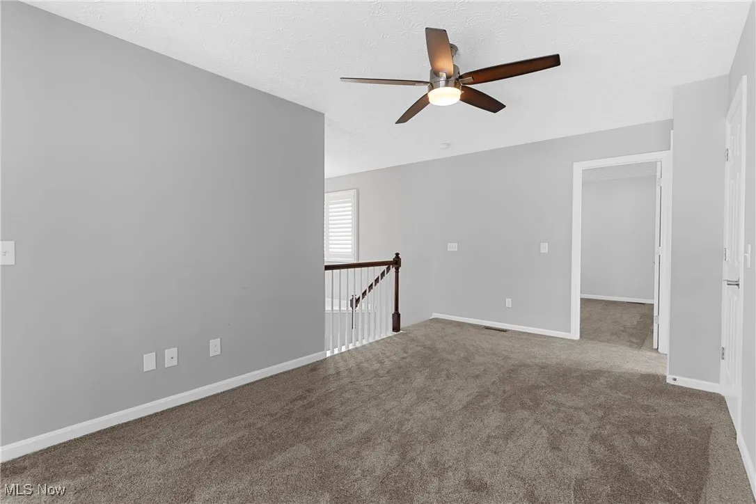 Carpeted spare room featuring ceiling fan and a textured ceiling