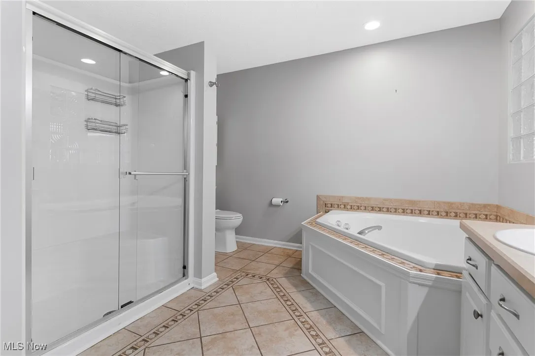 Bathroom with tile patterned floors, a shower stall, a garden tub, vanity, and recessed lighting