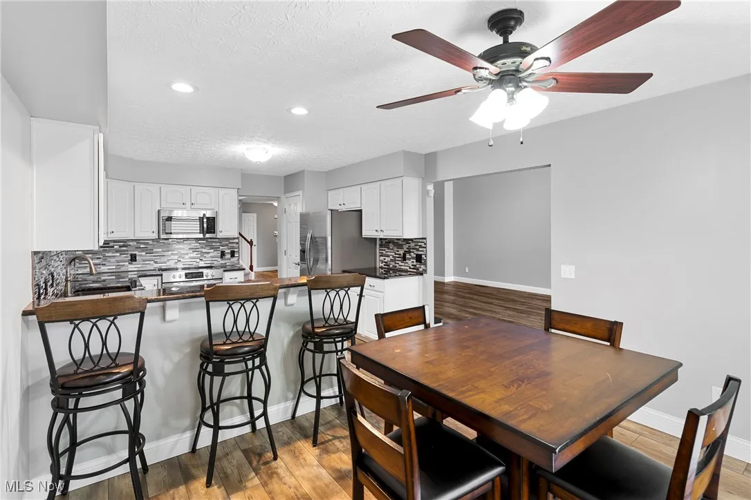 Dining area with a ceiling fan, recessed lighting, wood finished floors, and a textured ceiling