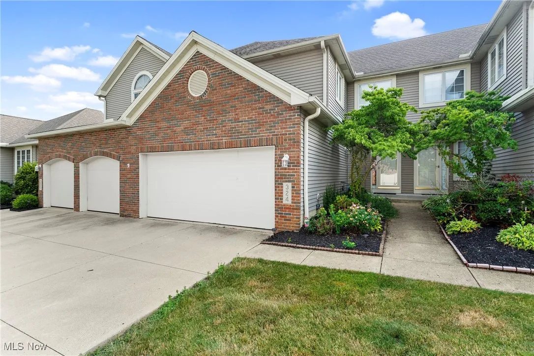 Traditional-style house featuring a garage, concrete driveway, and brick siding