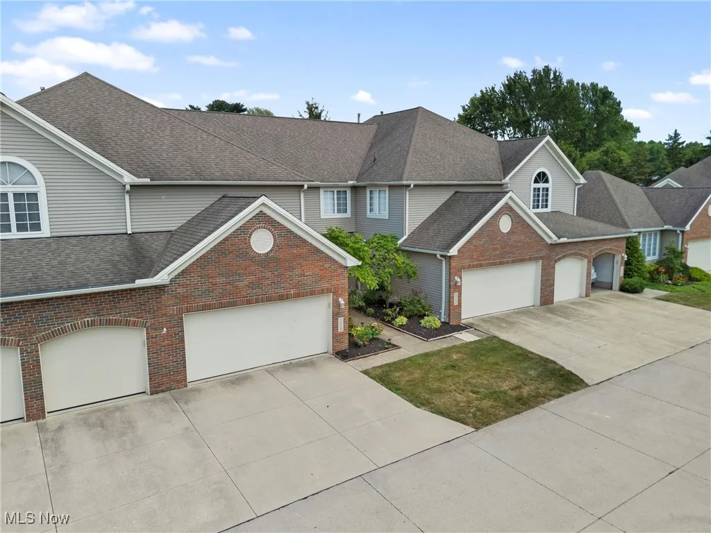 Traditional home with brick siding, concrete driveway, roof with shingles, and a garage
