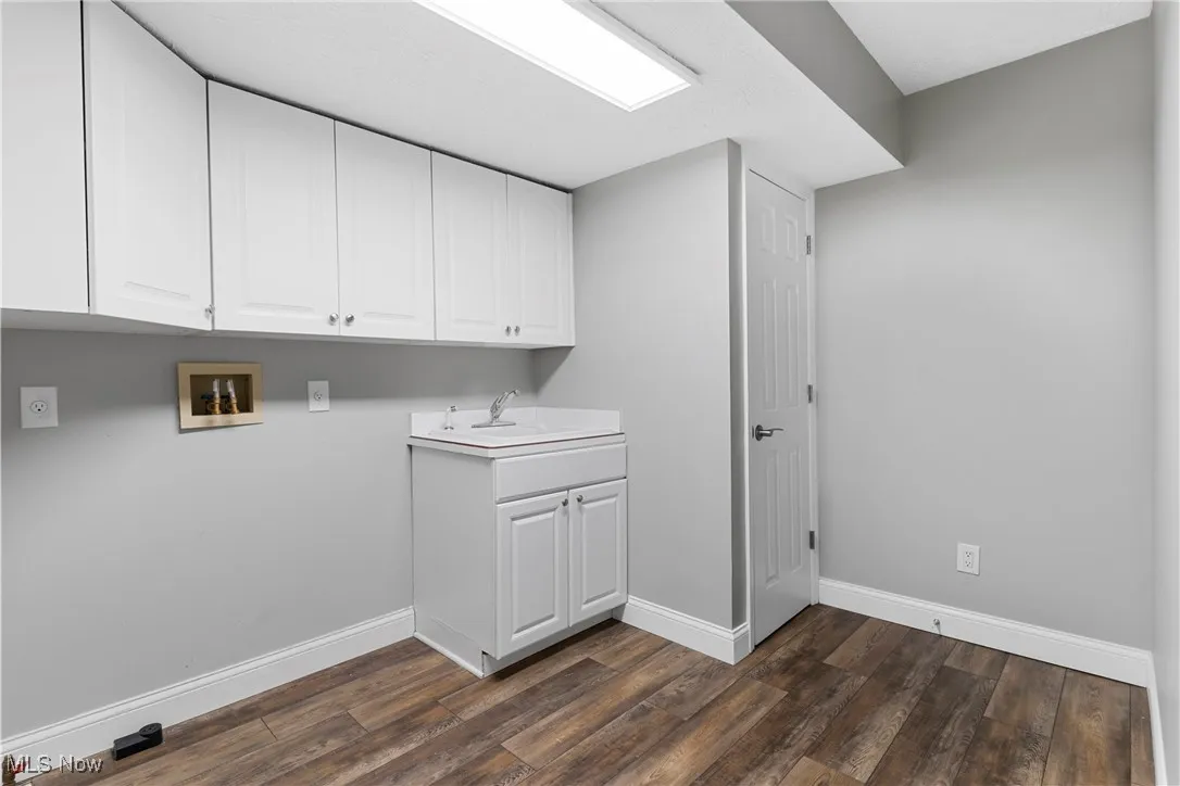 Laundry area featuring hookup for a washing machine, dark wood-type flooring, and cabinet space