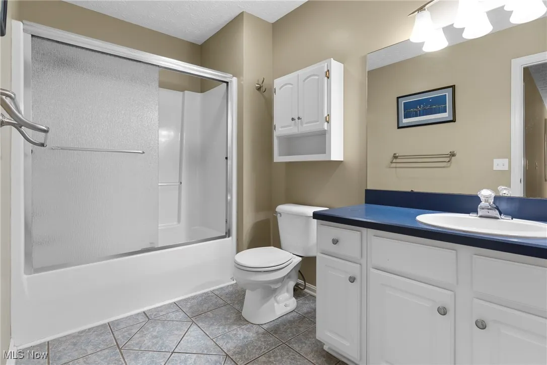 Full bath with vanity, tile patterned floors, and combined bath / shower with glass door