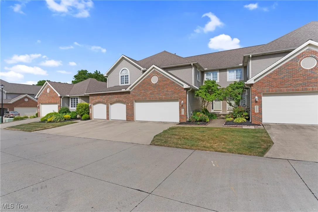 Traditional-style house with driveway, brick siding, a garage, and a front yard