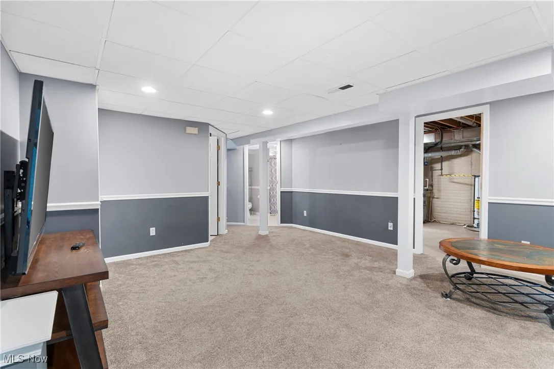 Finished basement with carpet floors and a drop ceiling
