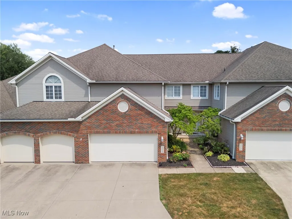 Traditional home featuring brick siding, roof with shingles, and driveway