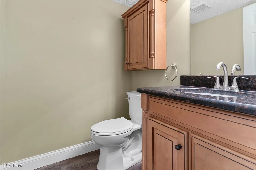 Half bathroom with vanity, wood finished floors, and a textured ceiling