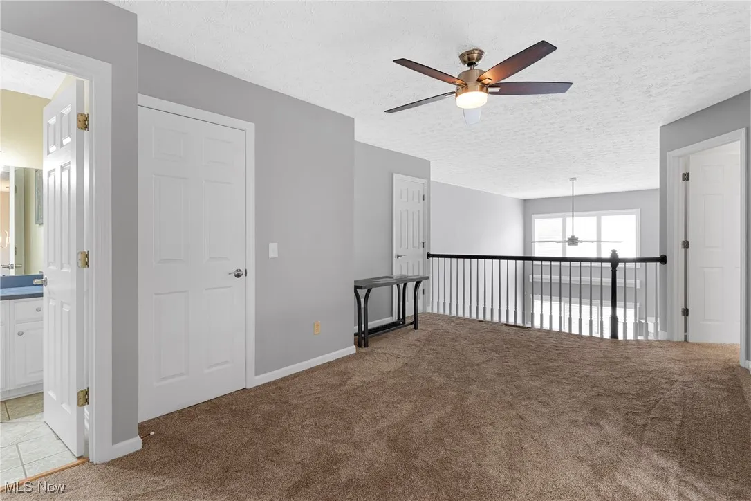 Empty room with ceiling fan, light carpet, a textured ceiling, and a chandelier