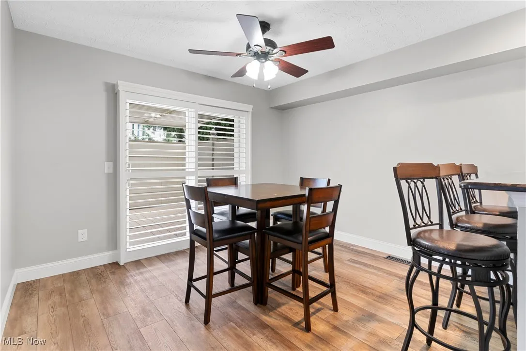 Dining room with a ceiling fan, light wood finished floors, and a textured ceiling