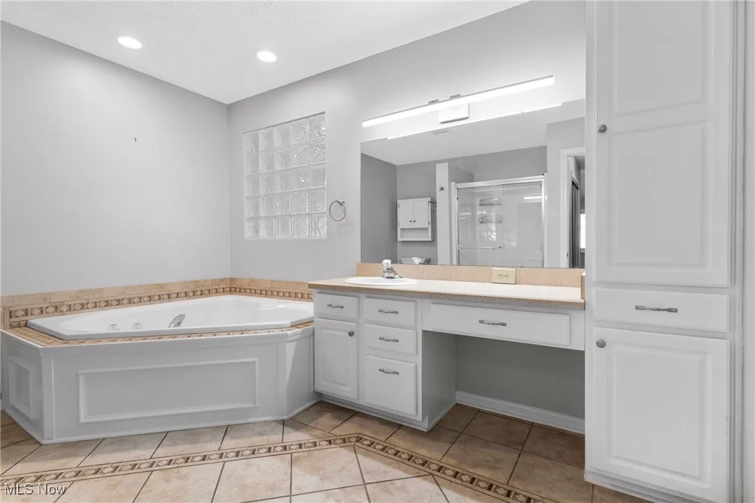 Full bath featuring tile patterned flooring, a shower stall, a tub with jets, vanity, and recessed lighting