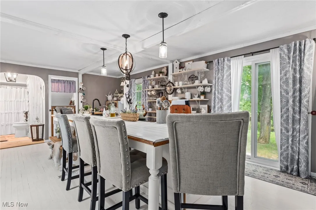 Dining space featuring plenty of natural light, wood finished floors, arched walkways, and beamed ceiling