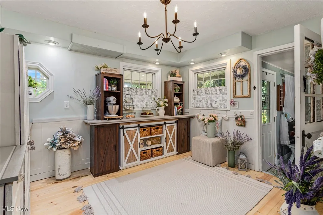 Bar featuring a chandelier, wood finished floors, wainscoting, and a decorative wall