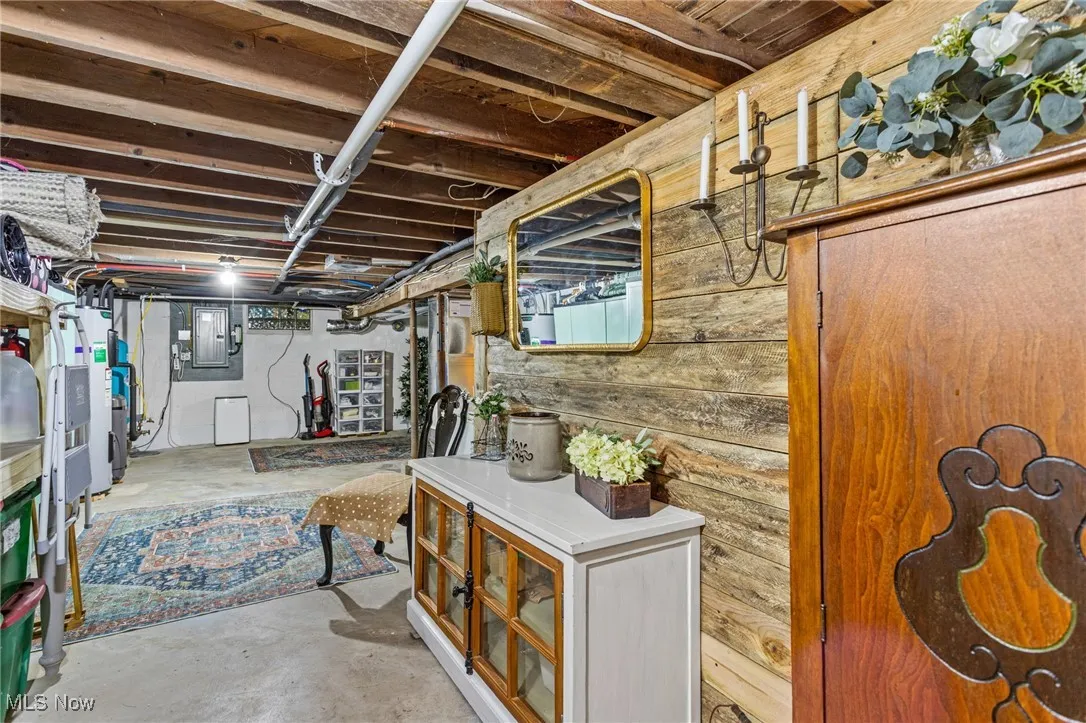 Unfinished basement featuring electric panel and wood walls