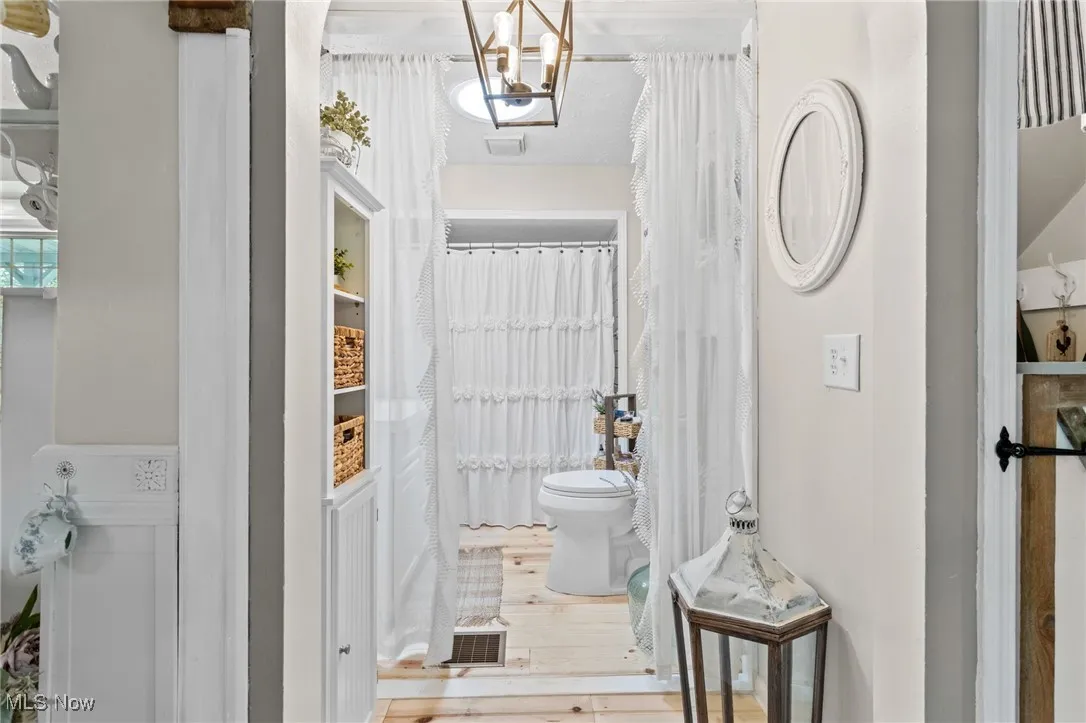 Full bathroom featuring wood finished floors and a chandelier