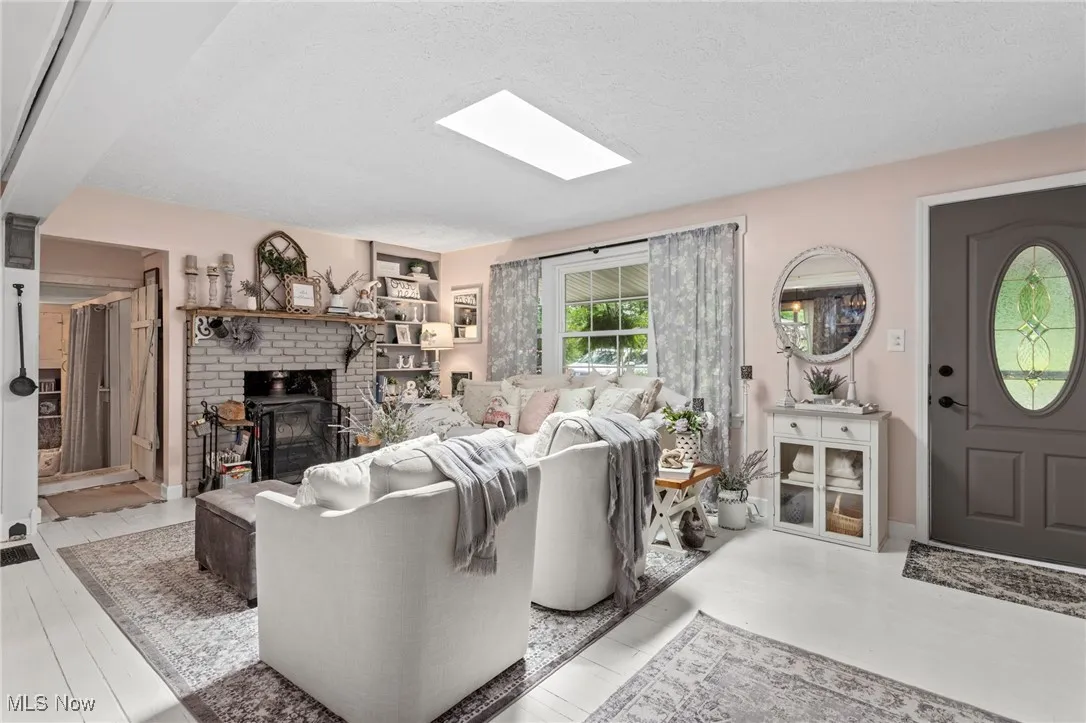 Living area featuring a fireplace, a textured ceiling, and a skylight