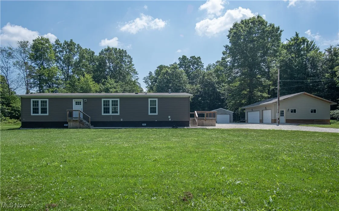 Manufactured / mobile home with a detached garage, a front yard, and an outbuilding