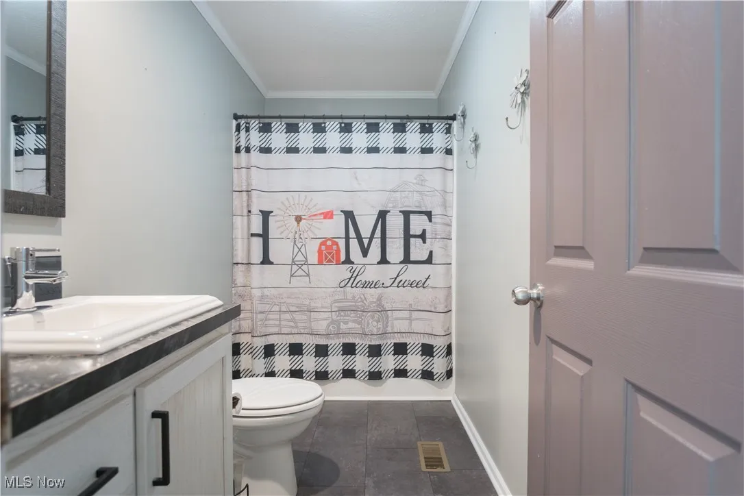 Bathroom with ornamental molding, vanity, and curtained shower