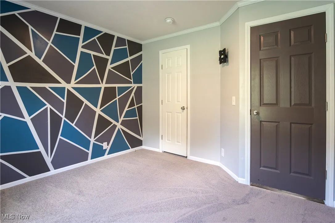 Empty room with crown molding, carpet, and a smoke detector