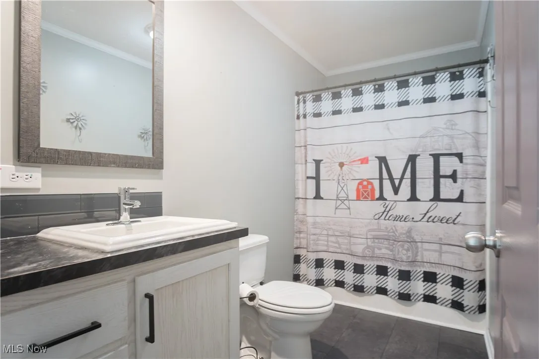 Full bathroom with vanity, ornamental molding, and shower / bathtub combination with curtain