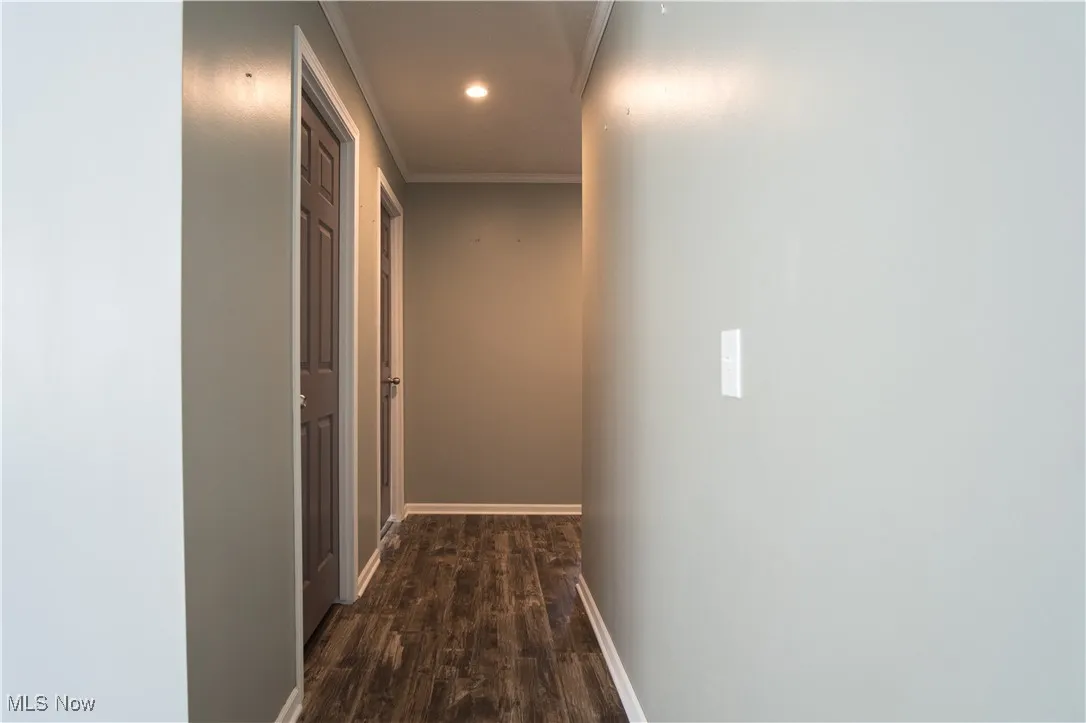 Hallway featuring dark wood-style flooring, recessed lighting, and ornamental molding
