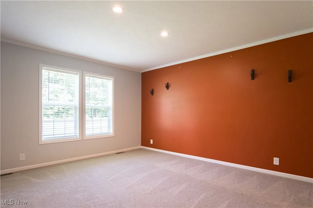 Spare room featuring light colored carpet, crown molding, and recessed lighting