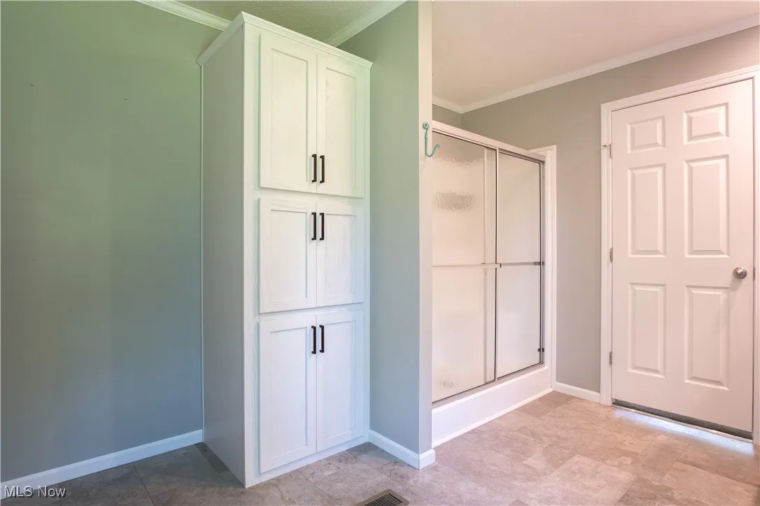 Bathroom featuring crown molding and a stall shower