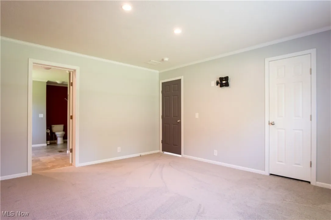 Empty room with crown molding, light carpet, and recessed lighting