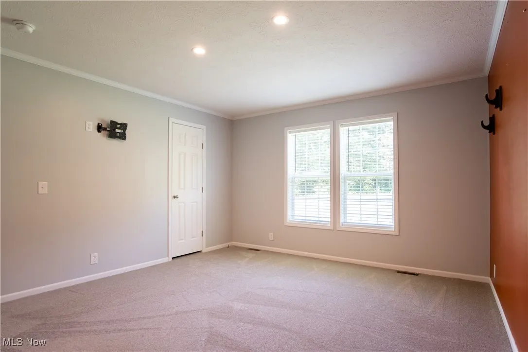 Spare room featuring light colored carpet, crown molding, a smoke detector, and recessed lighting