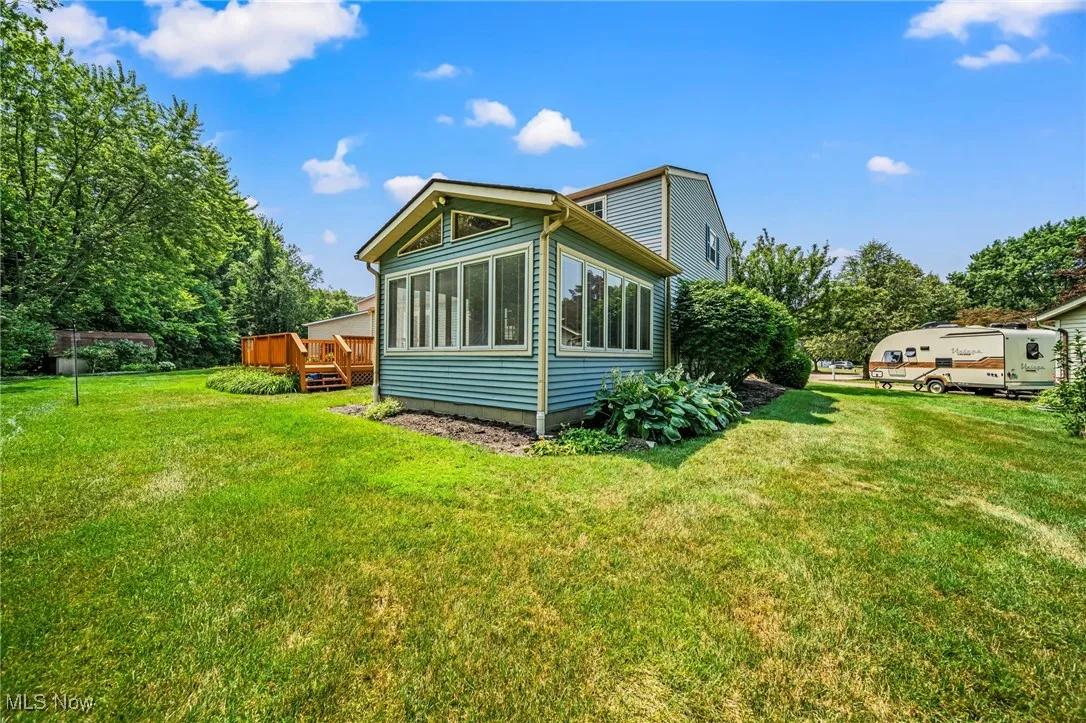 View of home's exterior featuring a deck, a yard, and a sunroom