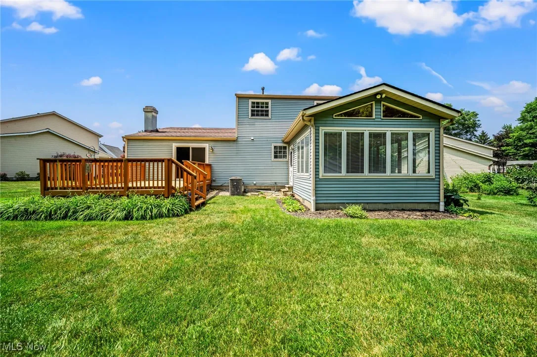 Back of house featuring a wooden deck and a yard