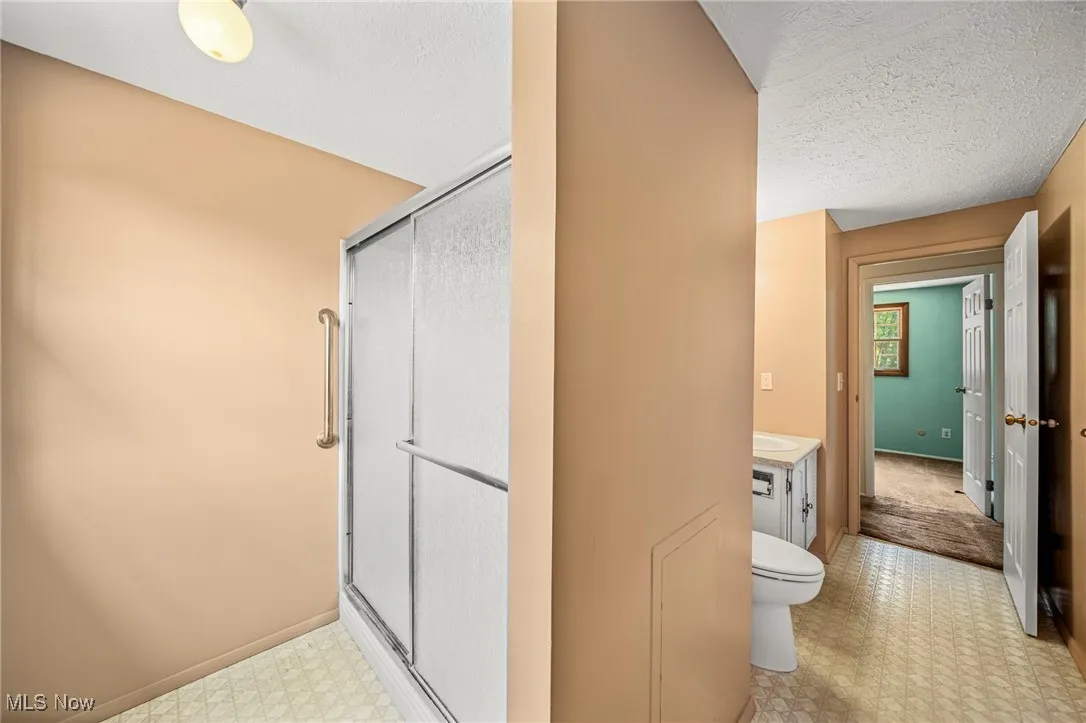 Full bath featuring tile patterned floors, a shower stall, vanity, and a textured ceiling
