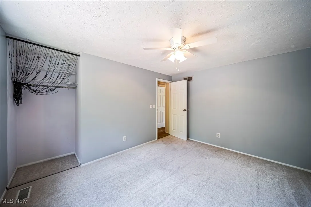 Unfurnished bedroom with carpet, ceiling fan, and a textured ceiling