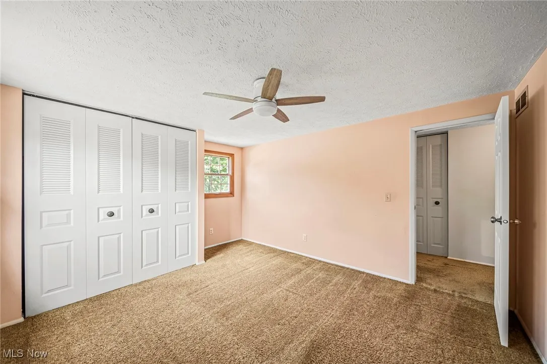 Unfurnished bedroom with carpet flooring, a textured ceiling, ceiling fan, and a closet