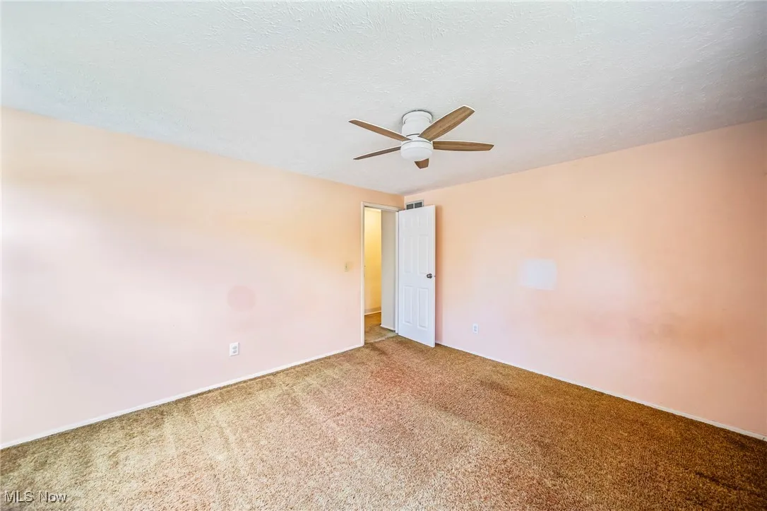 Carpeted empty room featuring ceiling fan