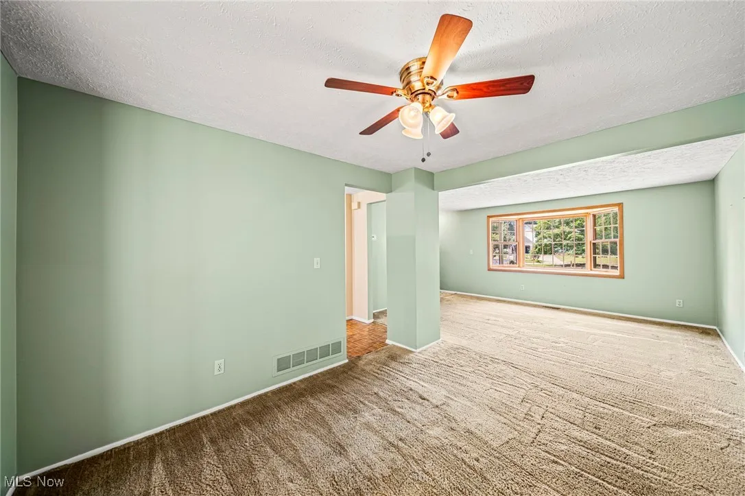 Spare room with a ceiling fan, a textured ceiling, and carpet