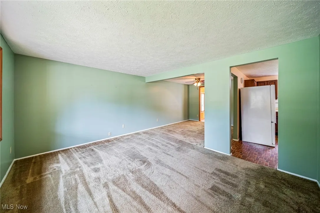 Carpeted spare room featuring ceiling fan and a textured ceiling