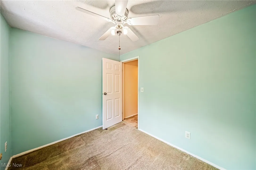 Empty room with carpet, a textured ceiling, and ceiling fan