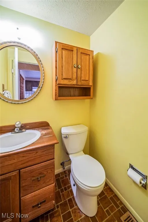 Half bathroom with vanity and a textured ceiling