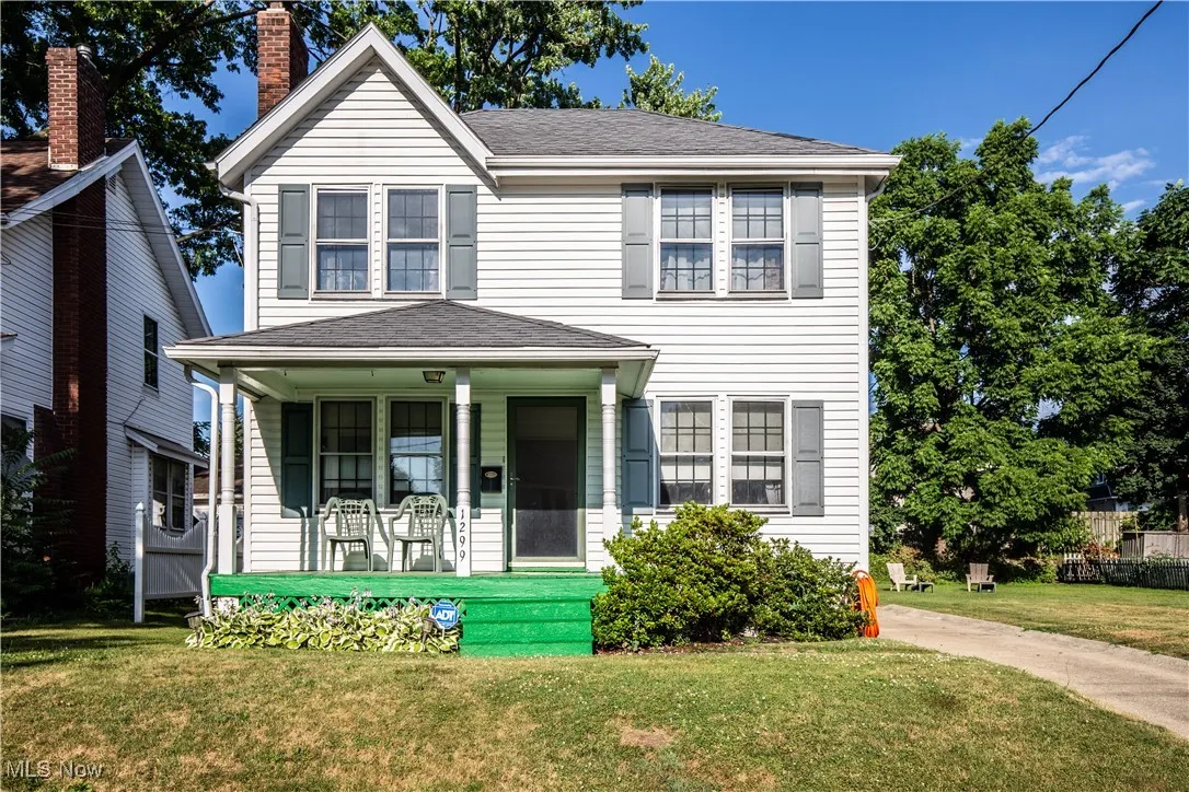 View of front of house featuring a porch, a front lawn, roof with shingles, and a chimney
